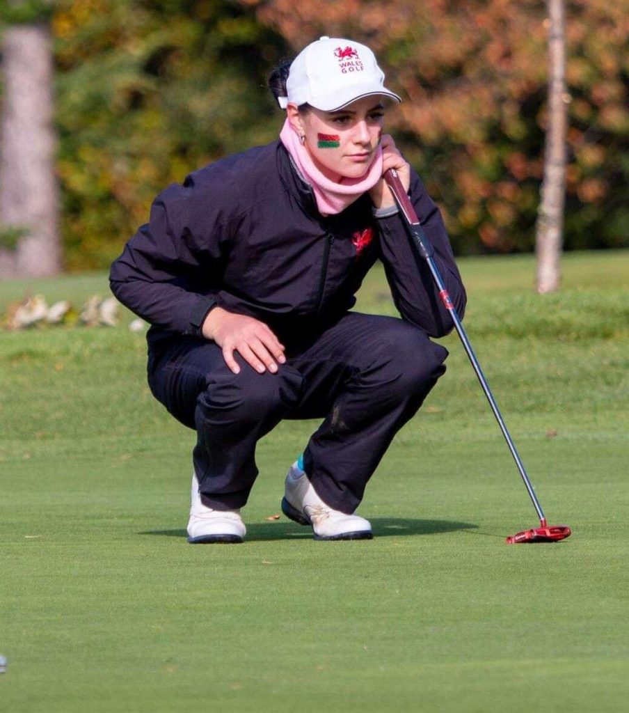 King's InterHigh pupil & talented golfer, Darcey, crouched down on the putting green, with a putter in hand & wearing golf attire.