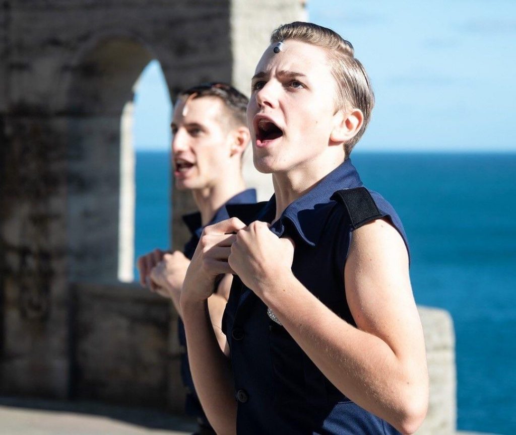 Student performing in a ruined castle next to the ocean.